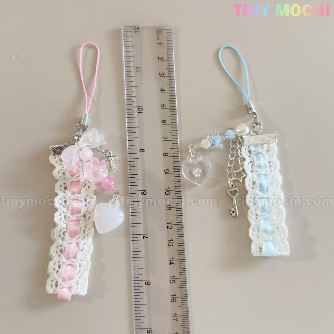 Two Tiny Mochi Kawaii Pastel Lace Ribbon Keychains—Heart & Star Bag Charms in pink and blue—are shown by a clear ruler measuring about 11 cm. These cute fairycore accessories stand out against a light background.