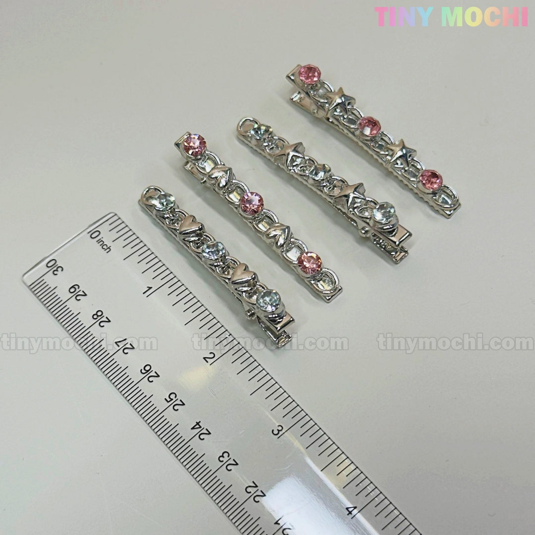 Four silver Kawaii Gem Hair Clips for Girls by Tiny Mochi, featuring star and heart designs with blue and pink gems, are displayed beside a transparent ruler on a light surface. Perfect sparkly Y2K pins for Coquette Aesthetic lovers.