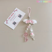 The Tiny Mochi Kawaii Angel Wing Keychain – Pink Heart Charm Bag Accessory features white plush wings, a pink bow, dangling beads and star charm, plus a pink strap and “TINY MOCHI” card with QR codes—perfect for soft girl style.
