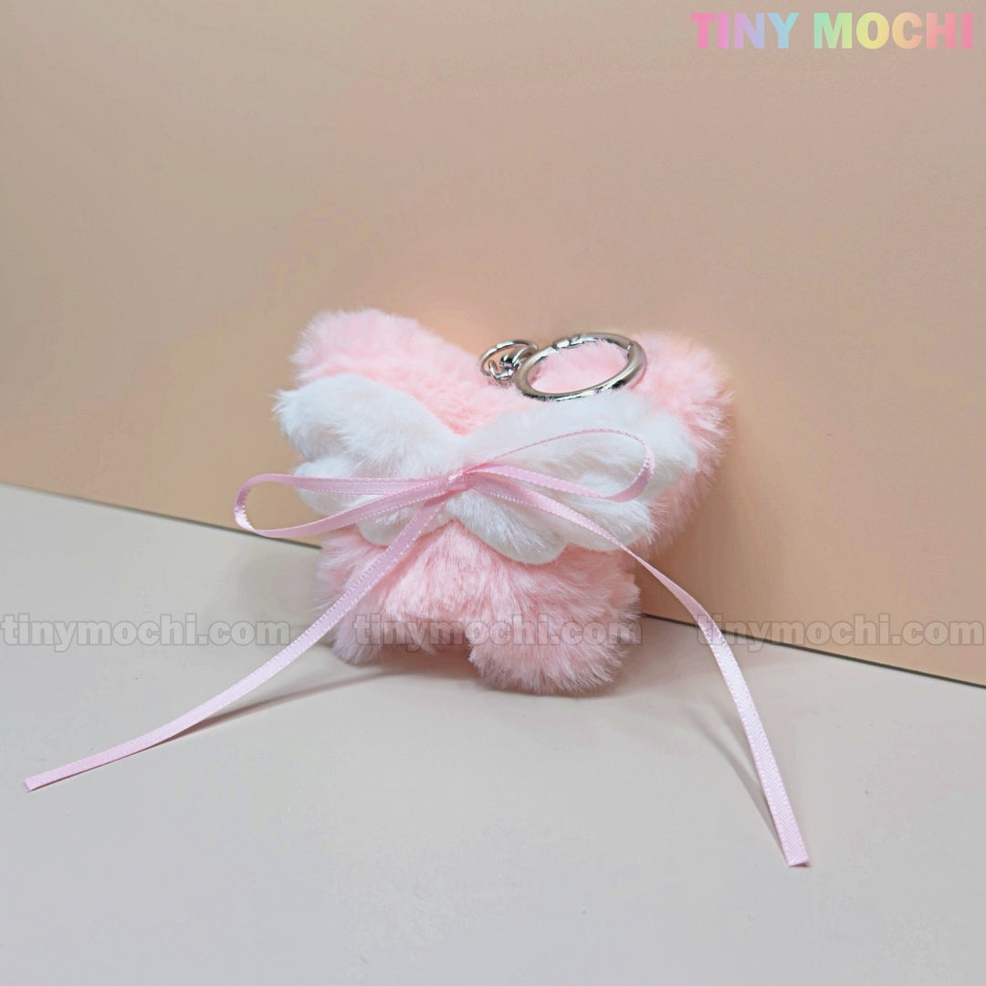 Add a coquette-inspired touch to your accessories with the Tiny Mochi Plush Butterfly Bow Keychain—a pink fuzzy bag charm featuring a cute ribbon bow, perfect for soft girl style or as a kawaii gift. Brand logo shown on a pastel background.