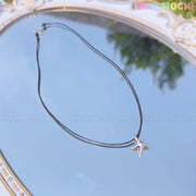 The Tiny Mochi Sterling Silver Starfish Necklace 925 Charm on Black Cord is shown atop a gold-detailed mirror reflecting blue sky and greenery, evoking minimalist ocean style. Tiny mochi watermark appears across the image.