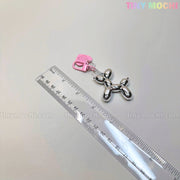 The Balloon Dog Keychain Chrome Silver Bag Charm with Pink Heart Tag from Tiny Mochi shines next to a clear ruler on a light surface, adding Y2K-inspired, soft girl flair. tinymochi.com appears subtly in the background.