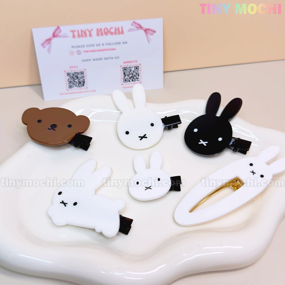 Five adorable Tiny Mochi Kawaii Bunny and Bear Hair Clips for Girls, featuring cute cartoon animals in white, black, and brown, are arranged on a white dish—fun aesthetic snap & alligator clips for any look.