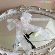 The Tiny Mochi Lace Bow Ribbon Keychain – Pearl Angelcore Bag Charm Clip features delicate lace with pink and white pearls, displayed on an ornate white and gold oval mirror. Pastel Tiny Mochi text appears, perfect for angelcore style or as a cute bag charm.