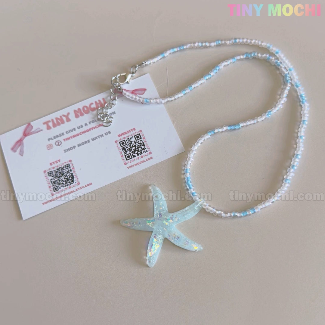 The Starfish Beach Necklace by Tiny Mochi features an iridescent blue starfish pendant and beads, perfect as handmade summer jewelry for girls and teens who love ocean aesthetic or mermaidcore style.