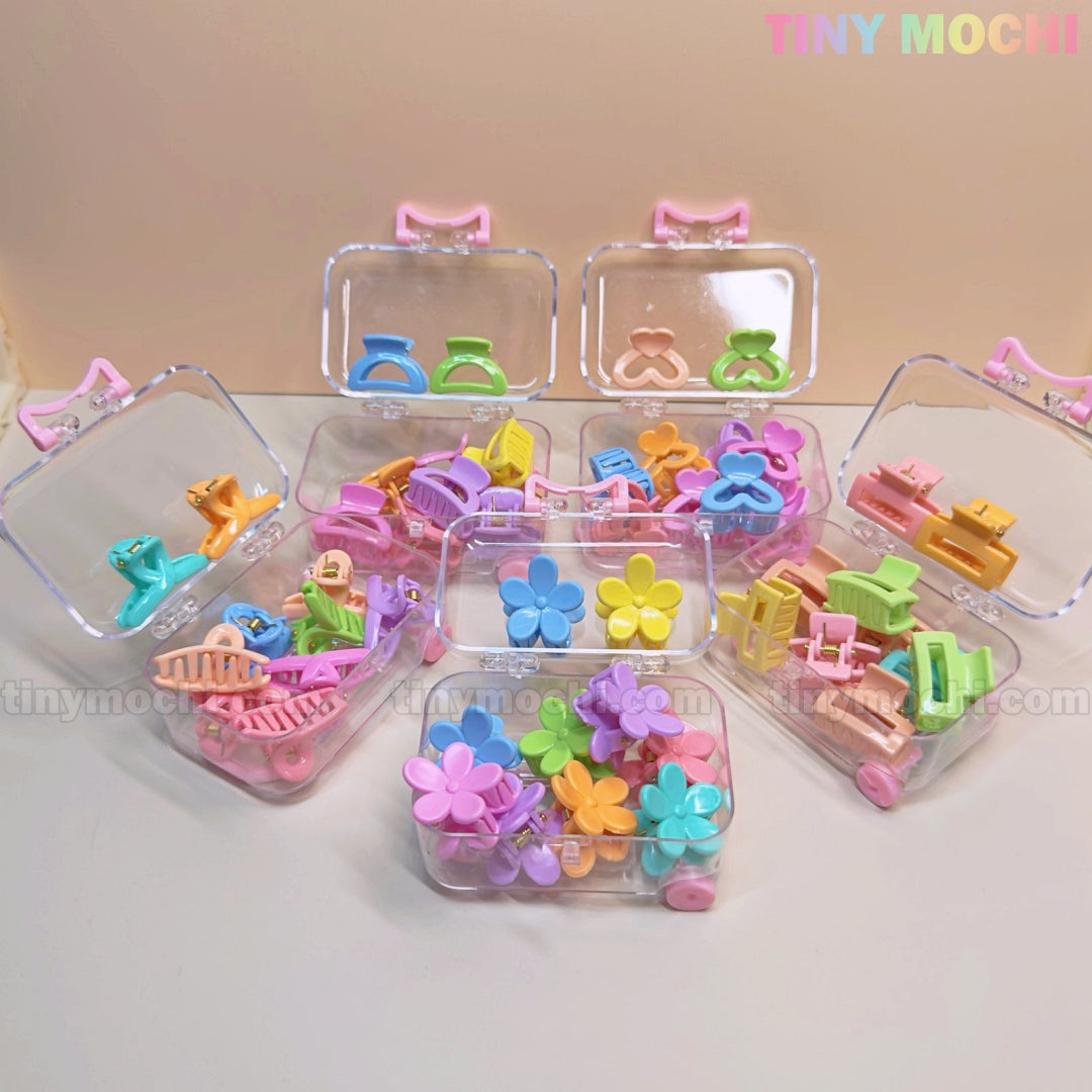 Tiny Mochi’s Kids Hair Clips Set features 10 colorful kawaii hair claws in butterfly, flower, and heart shapes, all neatly arranged in clear mini travel cases—perfect for kids and safely displayed on a light surface.