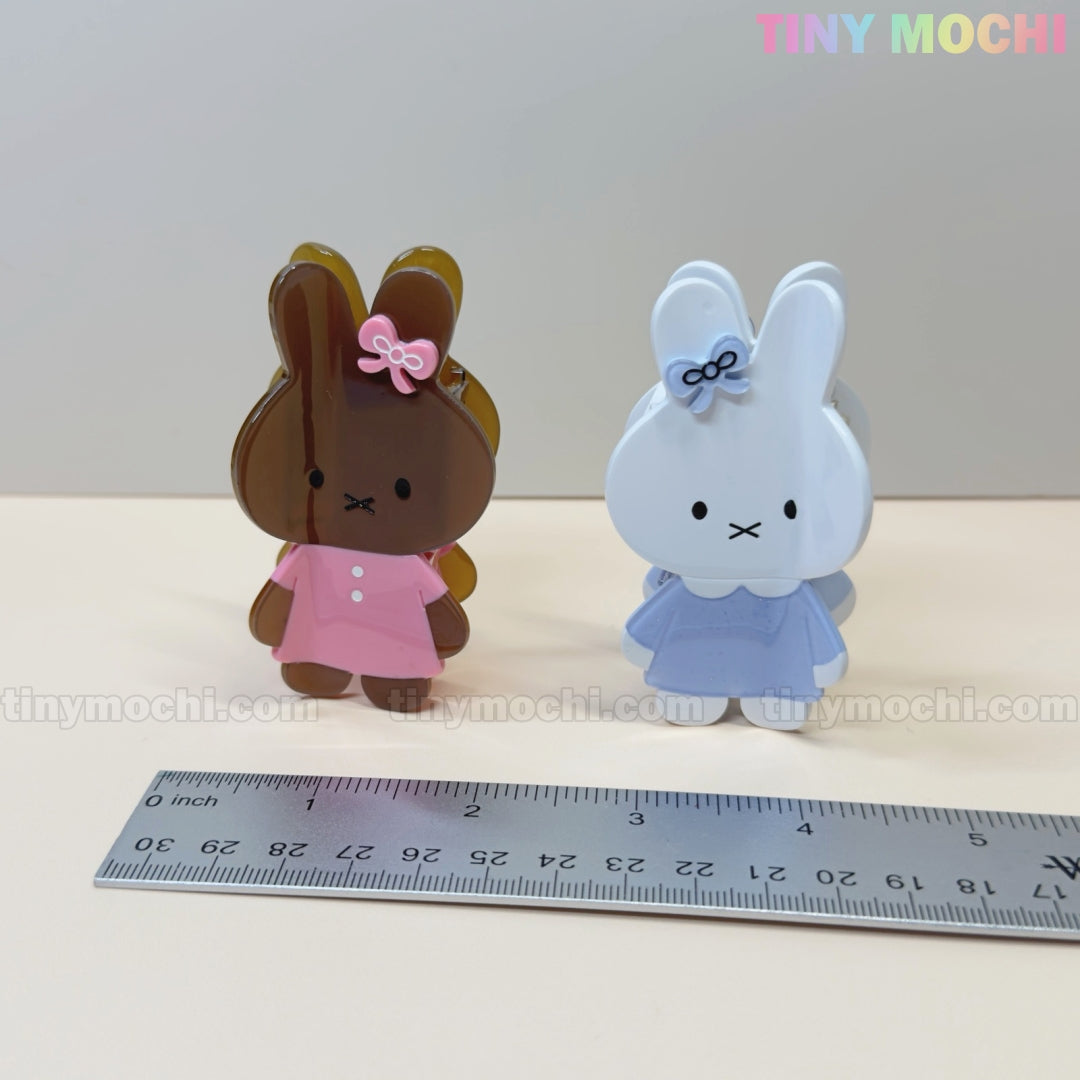 Two Kawaii Bunny Hair Claw Clips by Tiny Mochi—one brown in a pink dress, one white in a blue dress—sit side by side beside a ruler. Perfect pastel bunny hair accessories for adding cute flair to any look!.