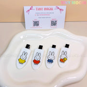 Four white Kawaii Bunny Hair Clips for Girls from Tiny Mochi, each with different Miffy rabbit outfits, are displayed on a tray. The Cute Cartoon Resin Alligator Clips make a perfect gift set for kids; Tiny Mochis card appears in the background.
