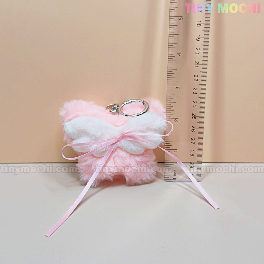 The Tiny Mochi Plush Butterfly Bow Keychain Pink Fuzzy Bag Charm is shown next to a ruler, measuring about 12cm tall. This soft girl purse accessory is perfect for coquette or kawaii style lovers! TINY MOCHI logo on a light peach background.
