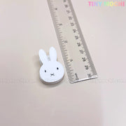 A clear ruler lies next to the Kawaii Bunny Paper Clip by Tiny Mochi, a cute Miffy-inspired white bunny face clip with black eyes, an x mouth, and TINY MOCHI in colorful letters—perfect desk decor and stationery accessory.