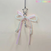 The Pink Star Bow Charm Keychain by Tiny Mochi features a pastel pink ribbon with pearls, silver star pendant clip, and wand charm—an adorable kawaii Y2K accessory for your phone or bag!.