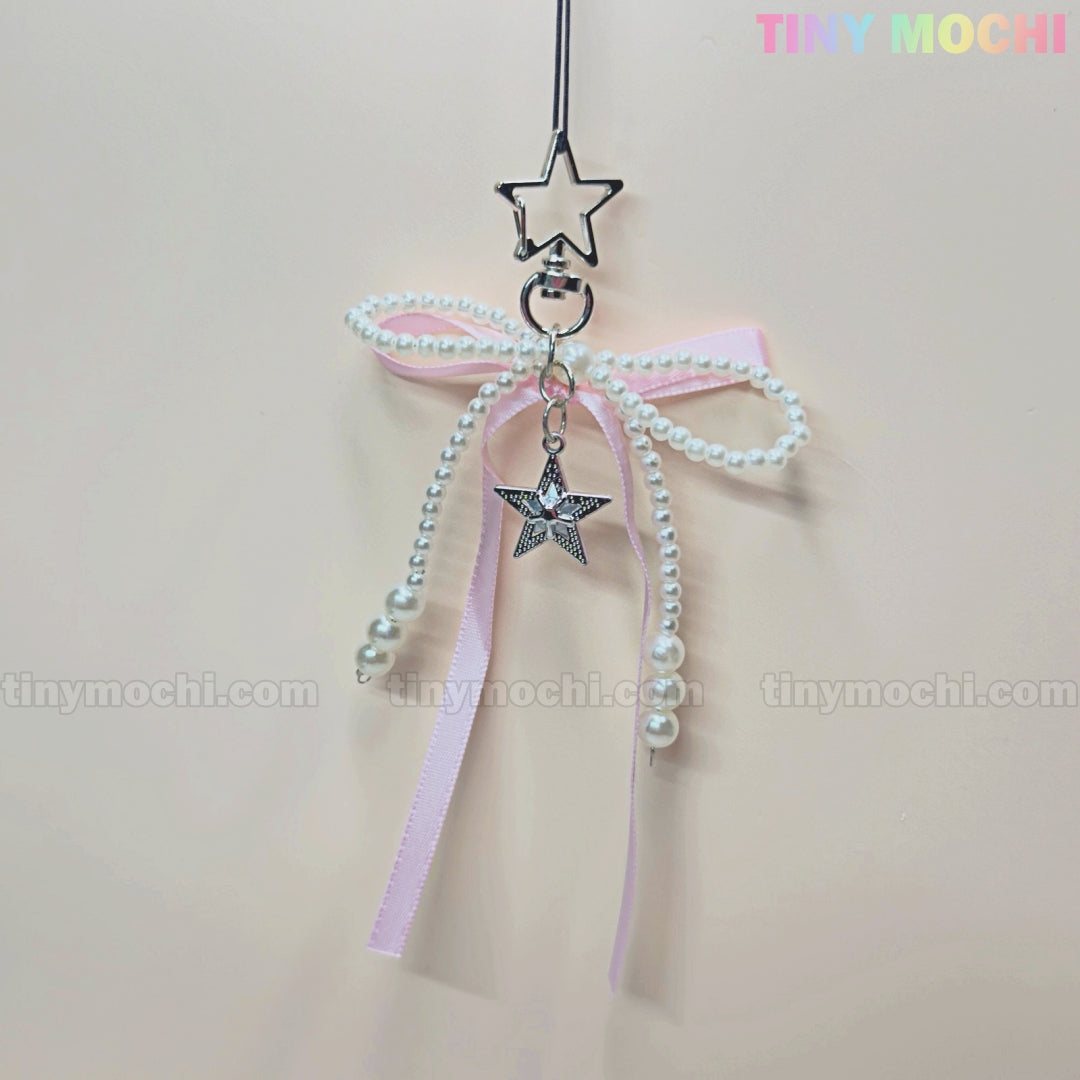 Add a kawaii touch with the Pink Star Bow Charm Keychain by Tiny Mochi! This coquette accessory features light pink ribbons, faux pearls, and a Twinkle Star Bow—perfect for your phone or bag. Pastel TINY MOCHI logo at the top right.