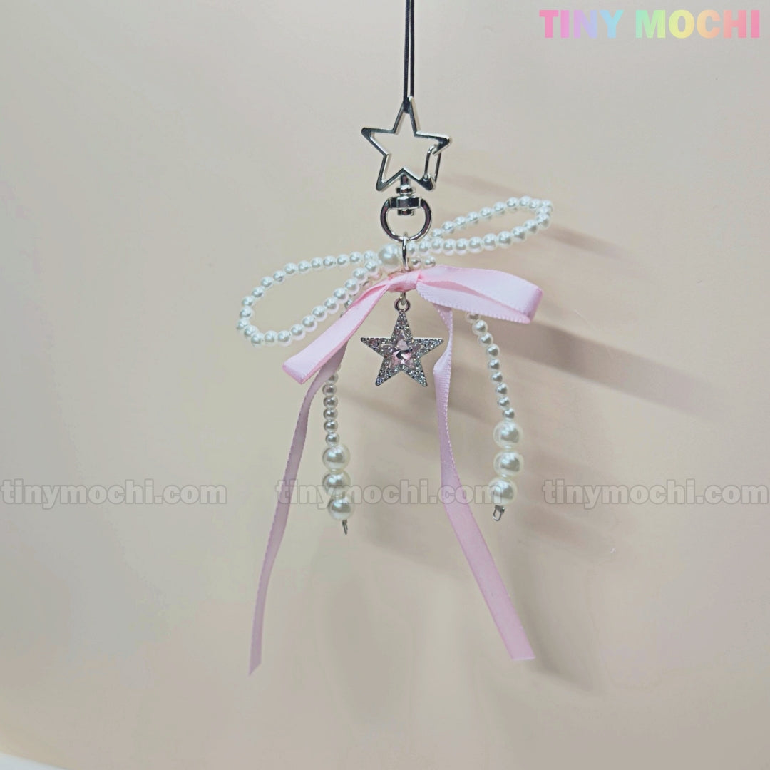 The Pink Star Bow Charm Keychain by Tiny Mochi features a star-shaped clip, pink ribbon, pearl beads, and a Y2K-inspired Twinkle Star Bow charm. Displayed on a pale background with TINY MOCHI in the top right corner.