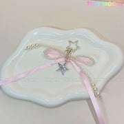 The Pink Star Bow Charm Keychain by Tiny Mochi features kawaii Y2K ribbon and pearl accents. Displayed on a white cloud-shaped dish with a pastel background, its the perfect coquette bag accessory or phone charm gift.