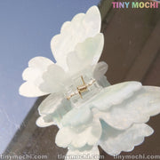 A close-up of Tiny Mochi’s Butterfly Hair Claw Clip, a UV changing color hair accessory crafted from durable acetate, reflected on a mirror. “TINY MOCHI” and “tinymochi.com” are displayed in the corners.