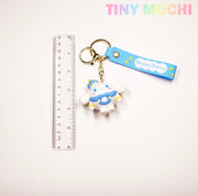 A ruler is next to the Tiny Mochi Cute Kawaii Character Keychain, a 3D anime-inspired charm with a blue Happy Party strap and a white character in a blue outfit—perfect for bags, keys, or as a unique gift for kawaii fans.
