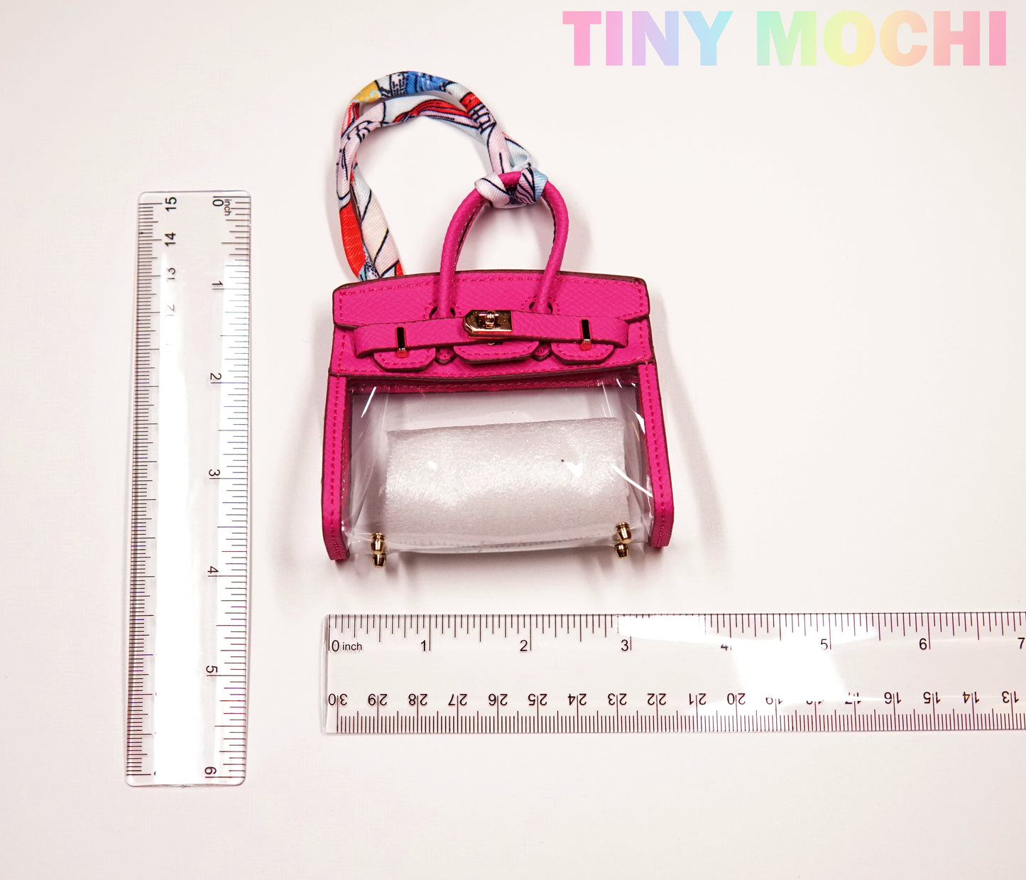 The Tote-Shaped Transparent Key Pouch by Tiny Mochi is a chic mini bag key holder for women, made of durable TPU—perfect as a fashionable and functional key organizer. Its size is shown between two rulers; Tiny Mochi appears in pastel at the top right.
