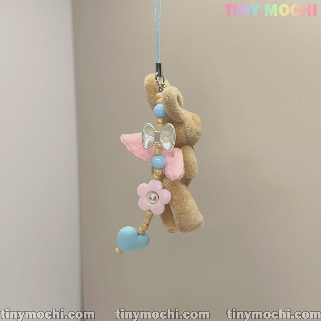 The Tiny Mochi Cute Pink Wings and Elegant Beige Soft Bunny Keychain, adorned with heart, flower, and pearl beads, hangs from a light blue string—an adorable charm for mobile devices, handbags, and more.
