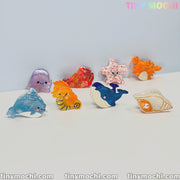 Cute Sea Creature Hair Clips by Tiny Mochi—featuring dolphin, seahorse, whale, shell, starfish, jellyfish, crab & coral designs—are neatly arranged on a white surface with tinymochi.com and TINY MOCHI branding visible.
