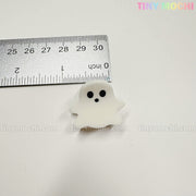 A metal ruler shows a ghost-shaped claw clip, about 1.5 inches tall, from Tiny Mochi Gift Shop Houston’s Kawaii Halloween Hair Claw Clips – Set of 8 Spooky-Cute Designs. Add charm to your hair accessories collection!.