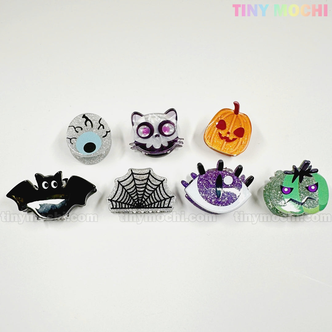 Add playful flair to your look with seven Halloween-themed pins and pair them with Kawaii Halloween Mini Claw Clips from Tiny Mochi Gift Shop Houston for extra spooky cute style!.