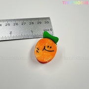 A cute orange veggie charm from the Kawaii Vegetable Hair Clip Set (8 pieces) by Tiny Mochi Gift Shop Houston is shown by a ruler for scale. Ideal for Halloween hair accessories, with tinymochi.com faintly visible in the background.
