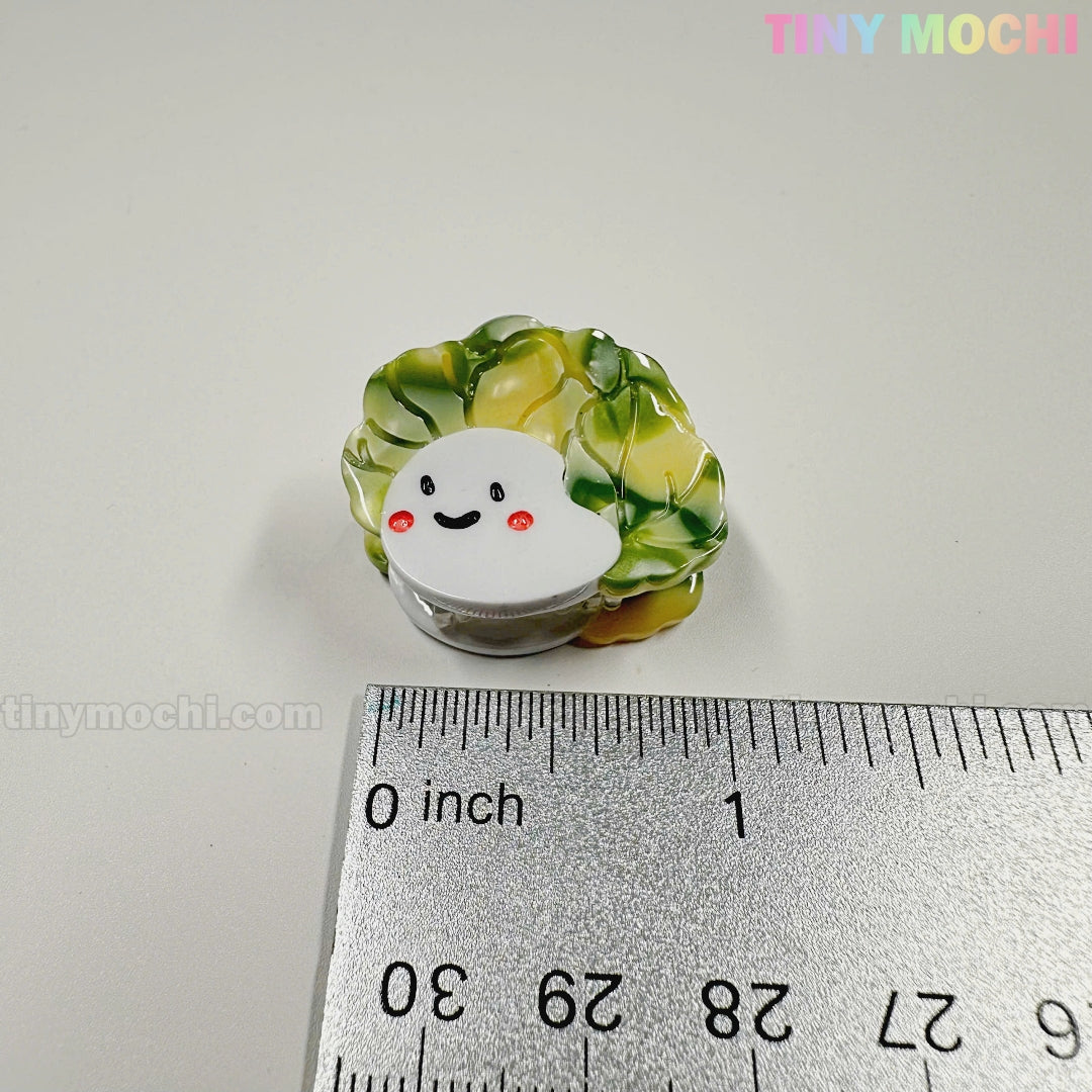 A cute enamel pin shaped like a smiling cabbage sits next to a ruler for scale. At about 1 inch wide, it pairs perfectly with the Kawaii Vegetable Hair Clip Set – 8 Pieces from Tiny Mochi Gift Shop Houston: Cute Accessories.