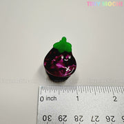 A small, glossy purple eggplant charm with a smiling face (about 2.5 cm tall) from the Kawaii Vegetable Hair Clip Set – 8 Pieces by Tiny Mochi Gift Shop Houston is perfect for cute hair clips or kawaii Halloween accessories.