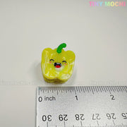 A cute small yellow bell pepper figurine smiles beside a ruler for scale. On a white background, "Tiny Mochi Gift Shop Houston" appears, promoting the Kawaii Vegetable Hair Clip Set – 8 Pieces among their adorable accessories.