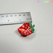 A metallic ruler measures a shiny red strawberry charm with green leaves, about 1 inch long, on a white surface. Fruity Friends Hair Clip Set by Tiny Mochi Gift Shop Houston: cute hair clips, keychains, bag charms & accessories.